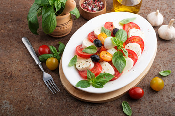 Delicious caprese salad with  tomatoes,mozzarella cheese and fresh basil leaves. Italian food. top view