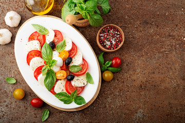 Delicious caprese salad with  tomatoes,mozzarella cheese and fresh basil leaves. Italian food. top view