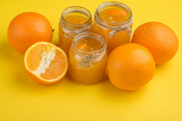 Orange jam in a glass jar on a yellow background. With empty space for writing