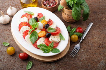 Delicious caprese salad with  tomatoes,mozzarella cheese and fresh basil leaves. Italian food. top view