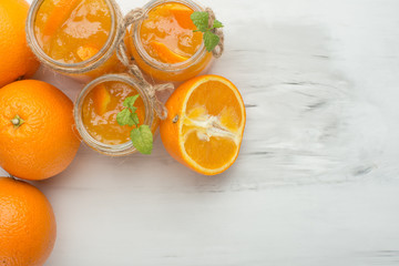 Orange jam in a glass jar on a light background. With an empty space for writing