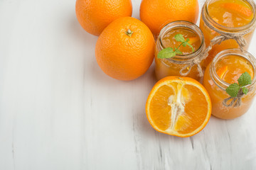Orange jam in a glass jar on a light background. With an empty space for writing