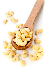Heap of raw, organic, whole cashew nut kernels in wooden spoon on white