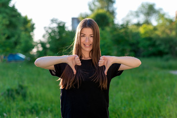 Girl brunette in fresh air. The Asian woman smiles slyly at the teeth of the braces. Hands gestures...