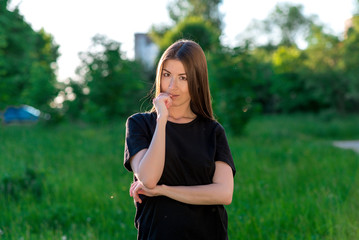 The brunette girl is European. In the summer in the park in the fresh air. With one hand he holds...