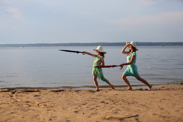 Dwie dziewczyny z parasolkami na brzegu jeziora.