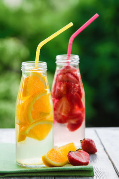 two ice fruit drinks on a wooden table in a garden background