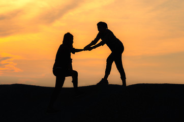 Fototapeta na wymiar silhouette two woman giving hand help her friend hiking climbing to mountain peak at sunset.