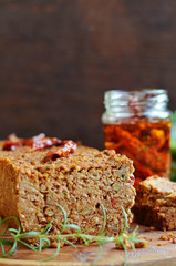 Lentil pate on a wooden background. Dried tomatoes in oil in the background