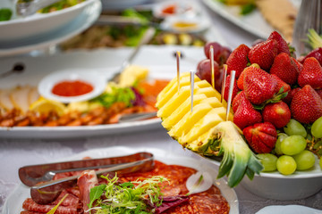Buffet table of reception with cold snacks, salads and fruits
