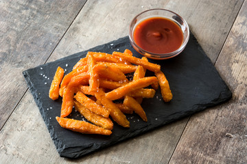 Sweet potato fries and ketchup sauce on wooden table