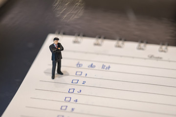 Business and planning concept. Businessman miniature figure standing on notebook with hand writing...