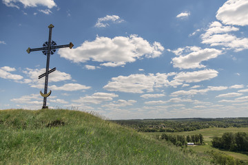 Black cross on the mountain against the blue sky