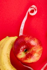 Measuring tape wrapped around a red apple and banana