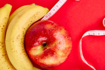 Measuring tape wrapped around a red apple and banana
