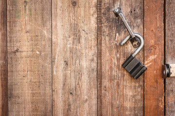 Vintage open padlock on an old shabby wooden door. Close-up view