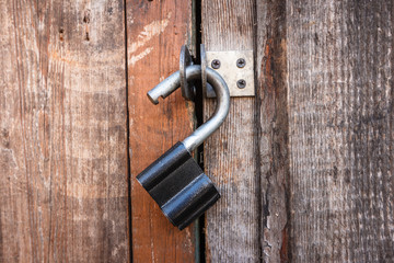 Vintage open padlock on an old shabby wooden door. Close-up view