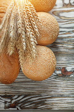 Bread long loaf ripe rye ears on wooden surface