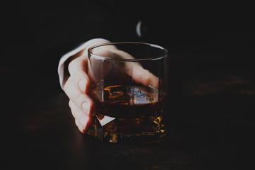 Glass with whiskey in hand, dark background, selective focus © 5ph