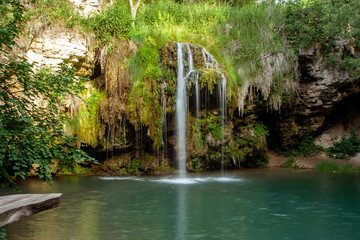 Obraz premium Waterfall and a beautiful lagoon lake for relaxing in the summer forest.
