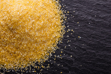 raw Italian corn porridge polenta on a dark stone background