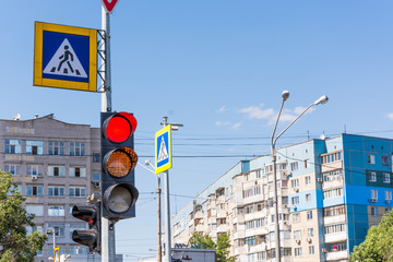 Red and yellow traffic light at the intersection of streets. Sign a pedestrian crossing. On a...
