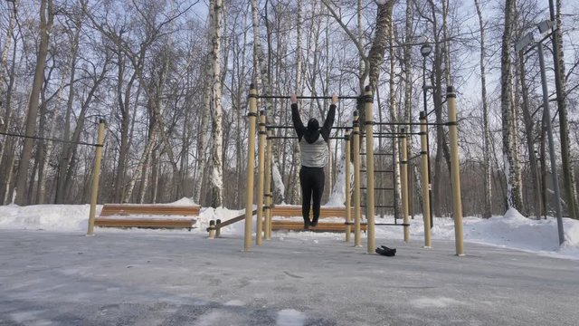 Athletic man training pull up exercise on winter gym workout on sport ground