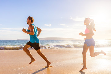 Jogging couple morning beach run healthy lifestyle. Active people training cardio workout together...