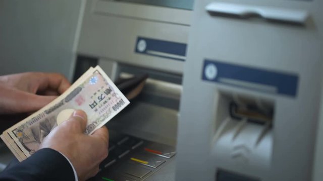 Man counting Japanese Yen withdrawn from ATM, putting cash in wallet, tourism