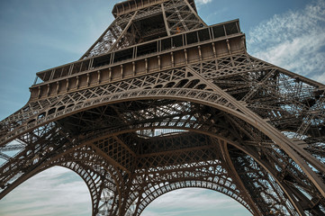 Bottom view of Eiffel Tower made in iron and Art Nouveau style, with sunny blue sky in Paris. Known as the “City of Light”, is one of the most impressive world’s cultural center. Northern France.