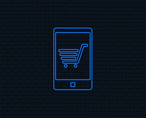 Neon light. Smartphone with shopping cart sign icon. Online buying symbol. Glowing graphic design. Brick wall. Vector