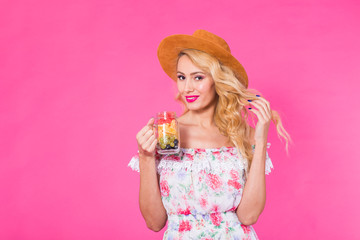 Young beautiful woman with fruit jar on pink background with copyspace