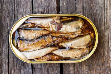 Open tin can of sprats on rustic wooden table