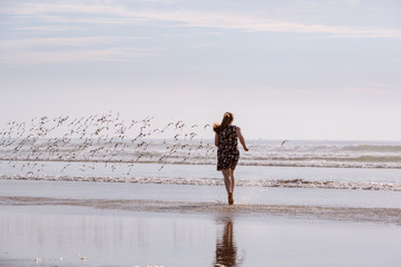 Woman Chasing Birds On Beach