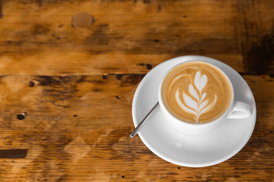 Cup of coffee to go on the wooden table with latte art. Street coffee. copy space