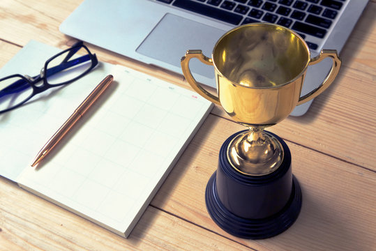 Trophy And Planing Book On Working Table , Winner Concept.