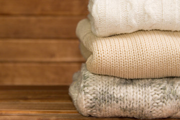 Obraz na płótnie Canvas Stack of cozy knitted warm sweater ,wooden background