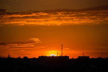 Sunset in the city with cellular tower and clouds
