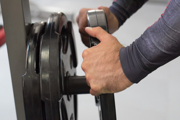 Hands add weigh plates to barbell in gym