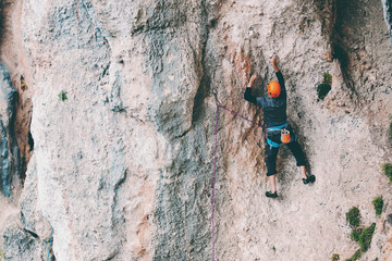 A man in helmet climbs the rock.