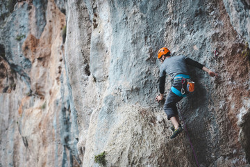 A man in helmet climbs the rock.