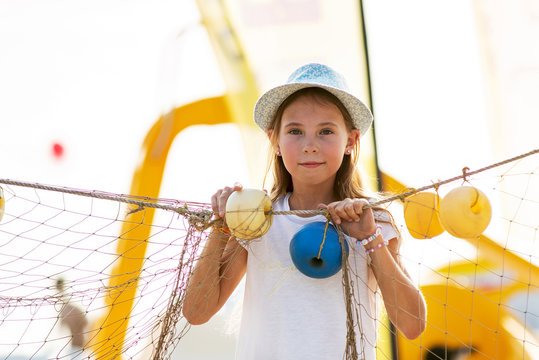 Young girl hiding behind fishing net on the beach 