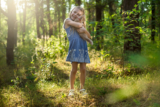 Little pretty girl  holds ginger kitten in the park