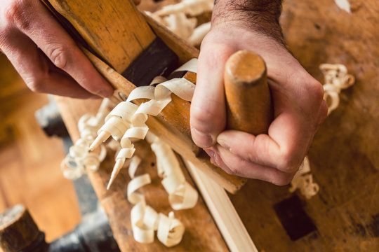 Draufsicht auf Hand von Tischler der mit Hobel an Brett arbeitet