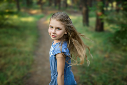 Portrait of little girl looks back in the forest