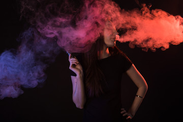 young woman smoking electronic cigarette on dark background