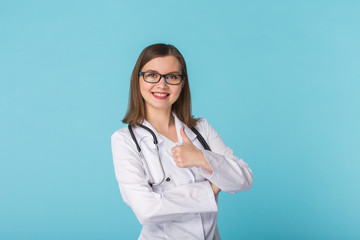 Portrait of woman doctor showing thumbs up over blue background