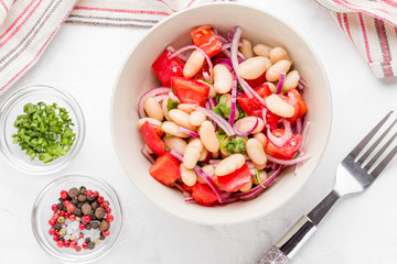 Salad with white beans, tomatoes, red onions, green coriander, parsley, delicious diet lunch
