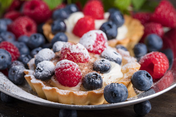 Fototapeta premium Dessert tarts with raspberries and blueberries on a wooden table.