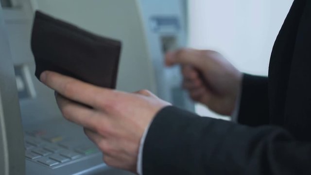 Male inserting card in ATM to withdraw cash and receive account balance report